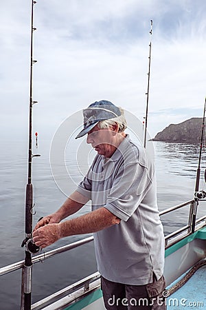 Retired senior male adult tourist on a fishing charter boat at M Stock Photo