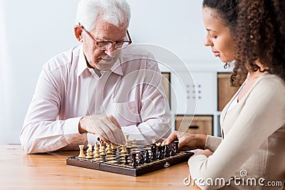 Retiree and caregiver playing chess Stock Photo