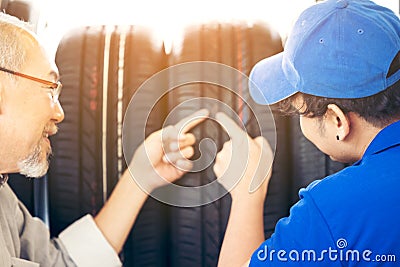 Retirement man touching and choosing for buying a tire in a supermarket mall. Measuring rubber car wheel Stock Photo