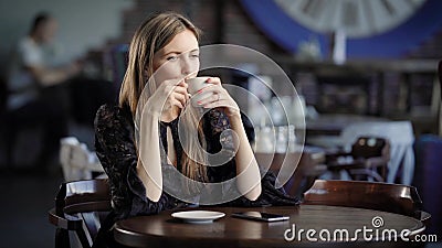 Retrato de uma mulher bonita em um café ou em um restaurante Uma menina bebe o chá ou o café e os sonhos sobre algo filme Retrato de uma mulher bonita em um café ou em um restaurante Uma menina bebe o chá ou o café e os sonhos sobre algo filme