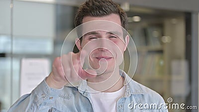 Retrato do jovem designer alegre apontando dedo na câmera Retrato do jovem designer alegre apontando dedo na câmera