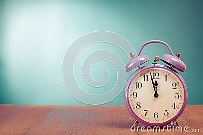 Retro alarm clock with five minutes to twelve o`clock on wooden table Stock Photo