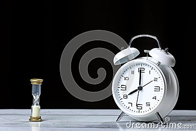 Retro alarm clock with sandglass in a black background. Morning. Break. Black background Stock Photo