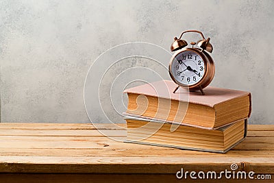 Retro alarm clock and vintage books on wooden table Stock Photo