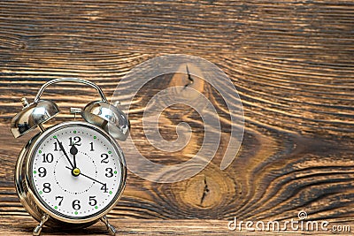 Retro alarm clock on a wooden background shows 12 hours, the space Stock Photo