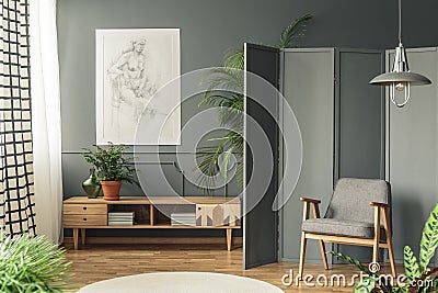 Retro armchair against a gray screen next to a drawing hanging o Stock Photo