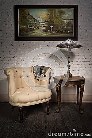 Retro armchair, table lamp on antique table and hanged painting Stock Photo