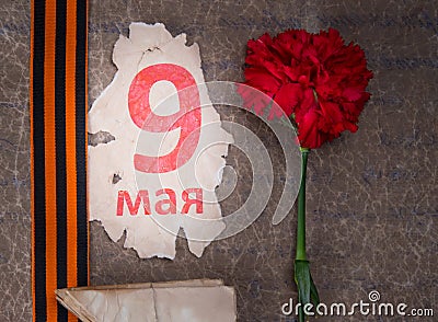 Retro background, may 9 inscription on a piece of paper and St. George ribbon, next to the red carnation Stock Photo