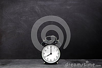 Retro black alarm clock showing eight o`clock with chalkboard background. Stock Photo