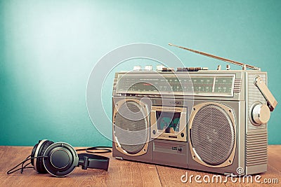 Retro cassette ghetto blaster and headphones on wooden table front mint blue background. Vintage style filtered photo Stock Photo
