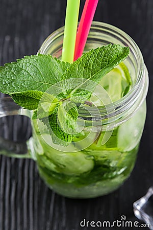 Retro glass jar of lemonade with cucumber and mint on wooden table. Cubes of ice Stock Photo