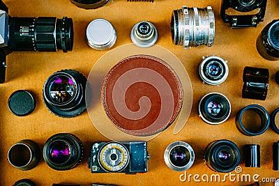Retro mockup, round leather vintage box in center and vintage photographic accessories and quipments around on wooden background. Stock Photo