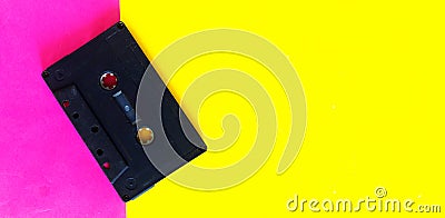 Retro old school 80-s or 90-s concept. Black Audio cassette on a pink yellow creative background Stock Photo