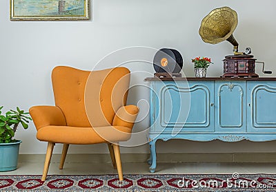 Retro orange armchair and vintage wooden light blue sideboard Stock Photo