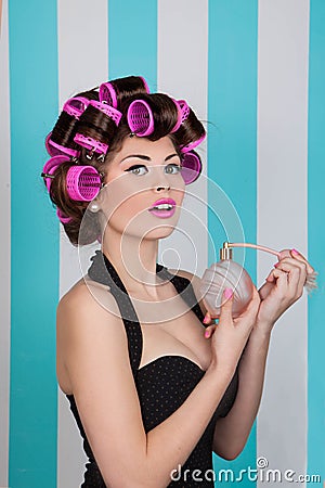 Retro pin up girl spraying perfume with hair rollers Stock Photo