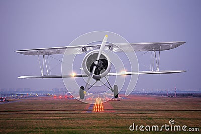 Retro plane fly up over takeoff runway from airport at twilight Stock Photo