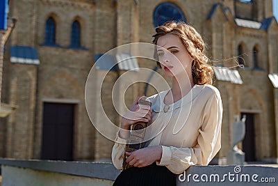 Retro portrait of a beautiful dreamy girl holding a book in hands outdoors. Soft vintage toning. Stock Photo