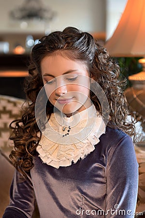 Portrait of a modest girl in an old-age interior and a vintage old-fashioned dress of the 1920s Stock Photo