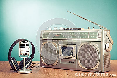 Retro radio and cassette player, headphones, microphone on wooden table front mint blue background. Vintage style filtered photo Stock Photo