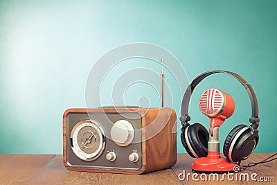 Retro radio, microphone and headphones on wooden table front mint blue background. Vintage style filtered photo Stock Photo