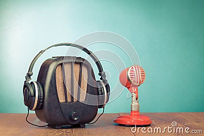 Retro radio, microphone and headphones on wooden table front mint blue background. Vintage style filtered photo Stock Photo
