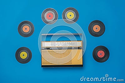 Retro radio and multicolored vinyl discs on a blue background. Radio engineering of the past time. Stock Photo