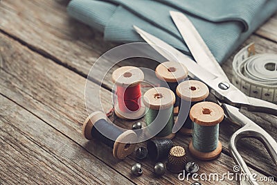 Retro sewing items - tailoring scissors, thimbles, buttons, wooden thread spools, measuring tape and green fabric Stock Photo