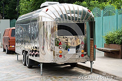 Retro style futuristic silver metal trailer van standing on summer day for fair, festival or event. Stock Photo