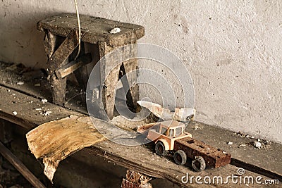 Retro toy car, wooden stool and piece of dirty paper, part abandoned house interior. Forgotten place. Stock Photo