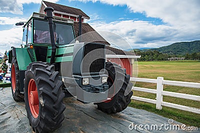 A retro tractor parked next to a barn in a farm.Thailand Stock Photo