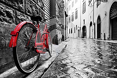 Retro vintage red bike on cobblestone street in the old town. Color in black and white Stock Photo