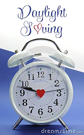 Retro vintage style white alarm clock on blue and white background with Daylight Saving with sample text Stock Photo