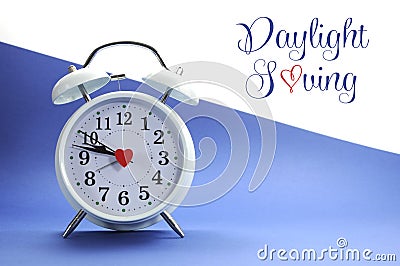 Retro vintage style white alarm clock on blue and white background with Daylight Saving sample text Stock Photo