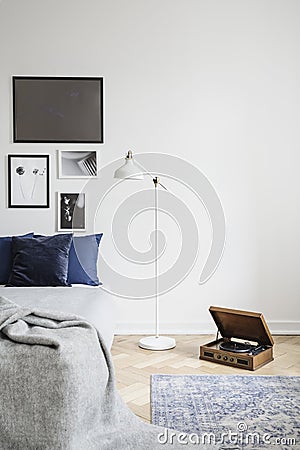 Retro vinyl record player and an industrial style floor lamp in a hipster bedroom with framed picture Stock Photo