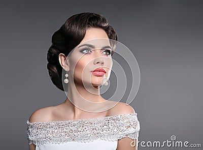 Retro woman portrait. Elegant lady with hairstyle, pearls jewelry set posing isolated on studio gray background. Stock Photo