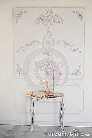 Retro wooden table with carved legs, a book, a chandelier with pink candles.The atmosphere of antiquity , the Stock Photo