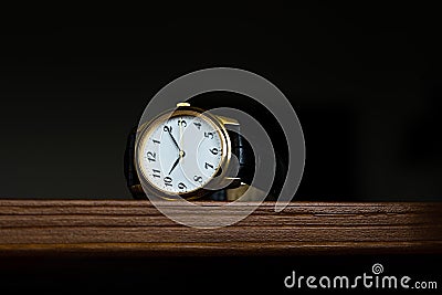 Retro wristwatch with Roman numerals on the dial on a wooden surface Stock Photo