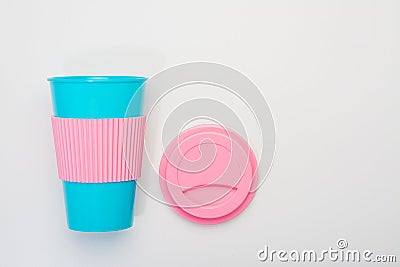 Reusable blue cup with pink silicone sleeve and lid for coffee, hot and cold drinks Stock Photo