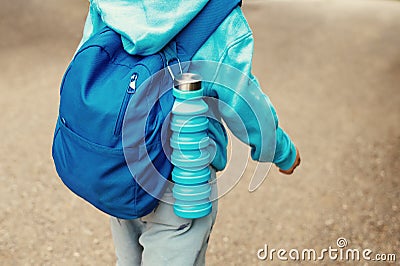 Reusable blue eco friendly water bottle on child`s backpack Stock Photo