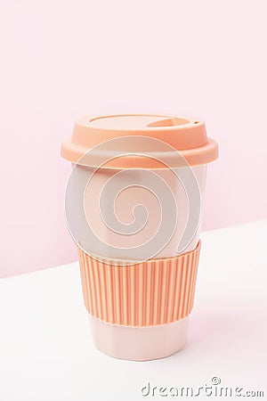 Reusable ceramic glass for coffee with silicone lid on pink and white background. Stock Photo