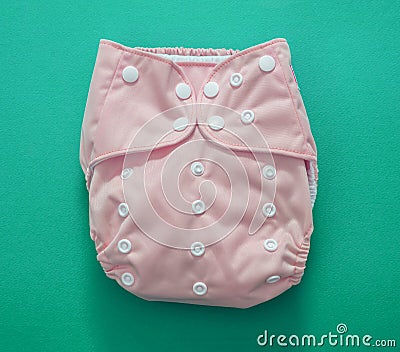 Reusable cloth baby diaper. Eco friendly nappy pink color on green background Stock Photo