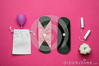 Reusable cloth pads and menstrual cup near disposable tampons on pink background, flat lay Stock Photo