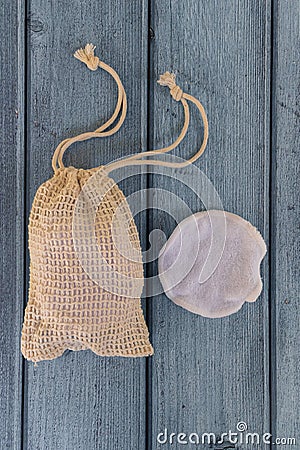 Reusable cotton make-up remover pad and eco bag on blue wooden background. Stock Photo