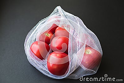 Reusable eco-friendly bag full of fresh seasonal tomatoes on black background Stock Photo