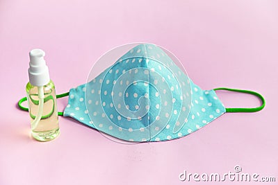 Reusable homemade fabric mask for the face and a sanitizer spray bottle. pink background Stock Photo