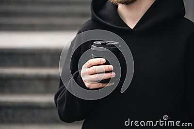 Reusable stylish bamboo black cup in the hands of a man, close-up. Stock Photo