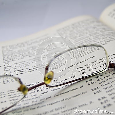 Review questions, electronic engineering book reading with glass on open page Stock Photo