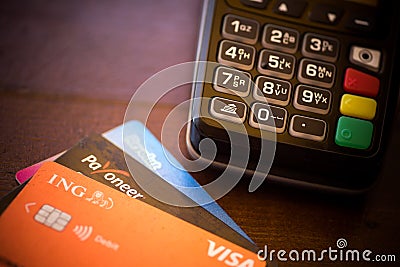 Revolut, ING and Payoneer cards near a POS terminal Editorial Stock Photo