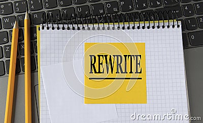 REWRITE - word on a yellow piece of paper on the background of a laptop with a notebook and a pen Stock Photo