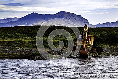 Reykhold, Southern Iceland, Iceland - July 31, 2019 - Construction Digger Along Small River Bank Editorial Stock Photo